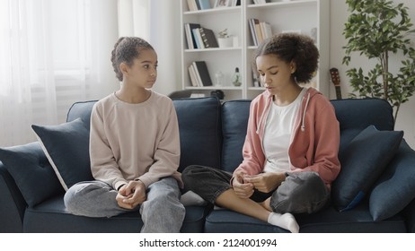 Black teenage girl telling bad news to best friend at home, sharing a secret