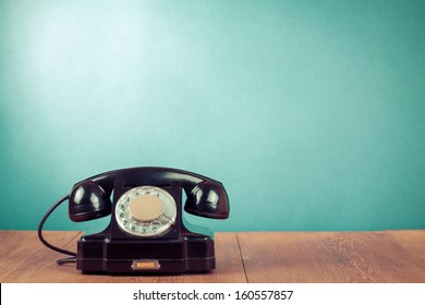 Black telephone on table in front mint green background