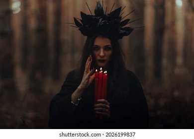 black terrible witch holds candles in her hands - Shutterstock ID 2026199837