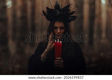 black terrible witch holds candles in her hands