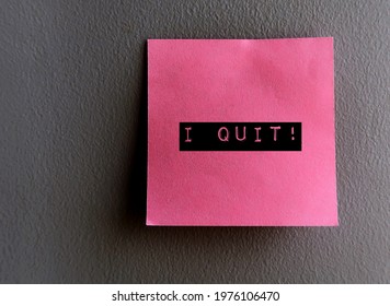 Black text on pink sticky note on grey wall written I QUIT , concept of giving up doing things or accepting defeat,resign or leaving from corporate job, quitting relationship or bad habit like smoking
