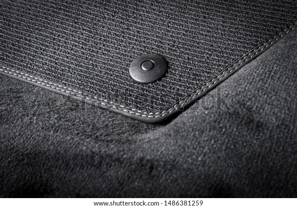 Black textile car mat with floor holders in black auto\
interior 