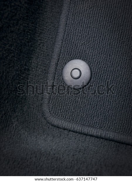 Black textile car mat with floor holders in dark\
car interior