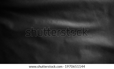 Black textile cloth flag, background abstract with soft waves. Close up drapery background with softness mood and tone. Realistic fabric texture