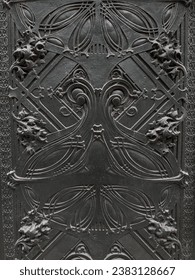 A black, textured gothic wall in Chicago, its intricate details and dark aesthetic highlighted by the stark contrast of broad daylight
