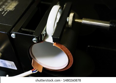 The black thermopress for cups, mugs is intended for transfer of the image or photo (sublimation). Сlose-up of a mug clamped in the thermopress. The process of transfer of the image on mugs, cups.