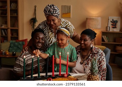 Black three generation family lightning Mishumaa Saba, seven colorful candles for Kwanzaa celebration - Powered by Shutterstock