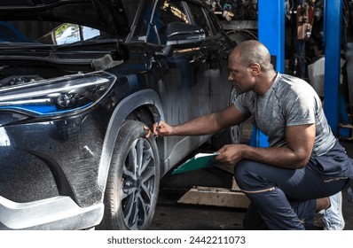 Black tire technician man checking car tire in auto repair and maintenance shop - Powered by Shutterstock