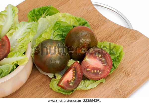 Black\
tomatoes , whole and cut on a chopping\
board.