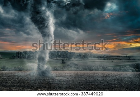 Black tornado funnel over field during thunderstorm
