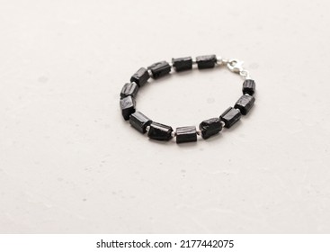 Black tourmaline, sherl bracelet. Bracelet made of stones on hand from natural stone Black tourmaline, sherl on light concrete modern background. Magic jewelry, lithotherapy and stone therapy.