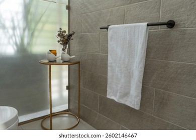 Tenedor negro de la toalla con la toalla blanca limpia en la pared ligera en baño moderno