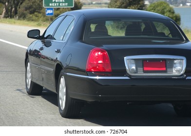 A Black Town Car Speeds Along The Highway.