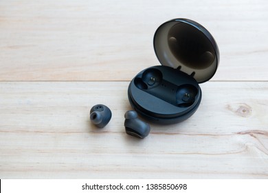 Black true wireless earbuds with power bank case on the wooden background