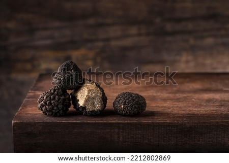 Black truffles in antique  wooden board, rustic style, low key, selective focus, macro, copy space for text. Season of black truffle. Autumn gourmet cuisine of Piedmont,  Italy, Spain and France Foto d'archivio © 