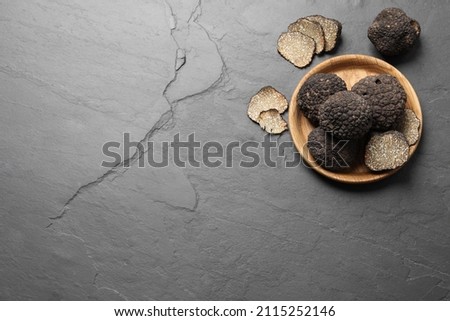Black truffles with wooden plate on grey table, flat lay. Space for text Foto d'archivio © 