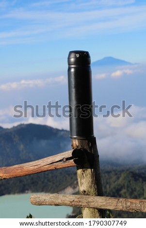 a black tumbler mug on wood fence with a landscape background