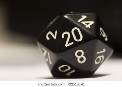 A black twenty-sided die with a 20 showing, on its side.