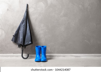 Black Umbrella And Gumboots On Floor Indoors