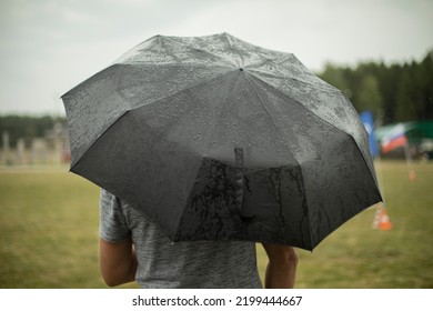 Black Umbrella In Rain. Large Umbrella In Bad Weather. Man On Street On Cloudy Day. Details Of Walk.