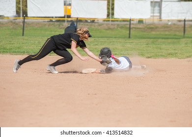 Black Uniform Softball Player Tagging The Player Sliding In White.