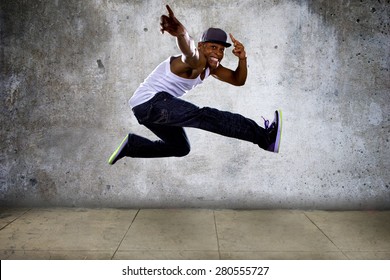 Black Urban Hip Hop Dancer Jumping High On A Concrete Background.  The Man Is Doing Parkour Or Leaping.