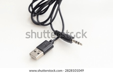 A black USB and audio jack cable lies on white