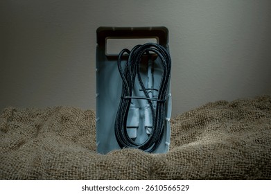 Black USB cable in plastic packaging on fabric background. Copy space.