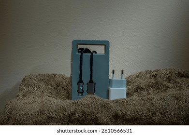 Black USB cable in plastic packaging on fabric background. Copy space.