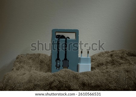 Black USB cable in plastic packaging on fabric background. Copy space.