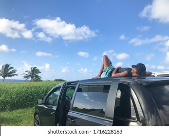 Black Van Car Roof. Man Relaxing Lay Down On The Car. Male Enjoying Sun And Taking A Nap During Road Trip Travel. Cap Covered His Face Protects The Sunlight. Concept; Relax,rest,freedom,enjoy,calm.