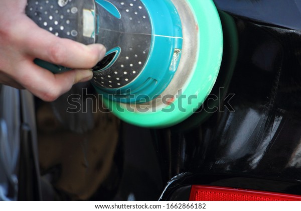 Black vehicle rear detail polishing with\
portable electrical eccentric polishing machine and soft circle\
close up, DIY car body\
renovation