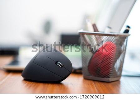 Black vertical optical computer mouse with ergonomic design. This mouse is designed to reduce injuries such as carpal tunnel syndrome, arthritis.