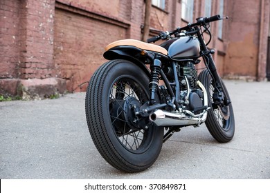 Black Vintage Custom Motorbike Motorcycle Caferacer In Front Of Brick Wall. Back View.