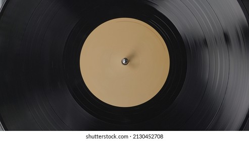 Black vinyl background with a beige screen in the center. A vinyl record on DJ turntable record player close up. Rotating plate and stylus with the needle close-up. - Powered by Shutterstock