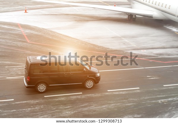 Black VIP\
service van running on airport taxiway with blurred private jet on\
background. Business class service at airport. Security\
intelligence agency hurrying at\
airfield