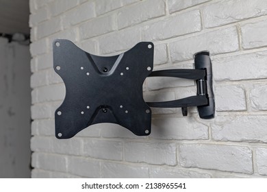 A Black Wall Bracket For TV On A Background Of White Decorative Brick. Metal Equipment For Machinery.