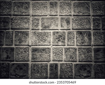 Black wall made of bricks arranged in a row of different sizes. and there are light and dark parts make it look dimensional