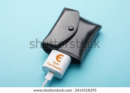 Black wallet and charger for a smartphone on a blue background, concept on the topic of extra income