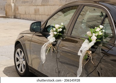 A black wedding car decorated with white roses