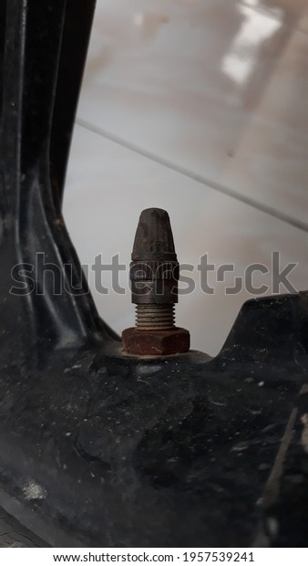 A\
black wheel valve complete with a cap above and a nut below it.\
Photos are suitable for articles about\
motorcycles