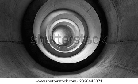 A black and white abstract image of a circular staircase descending into a dark, mysterious void.