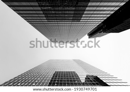 Black and white abstract low angle view of modern glass buildings with beautiful reflections in downtown financial district on clear sky background. City skyscrapers and business concept. Copy space.