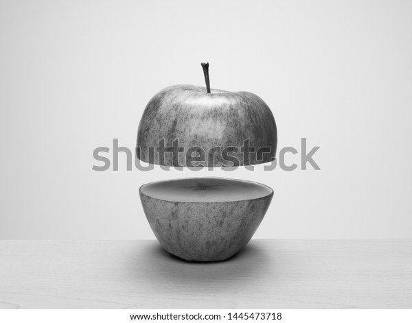 Black and white\
apple cut in half, separated and floating apart. Concept: parts,\
apart, float, levitate,\
separation