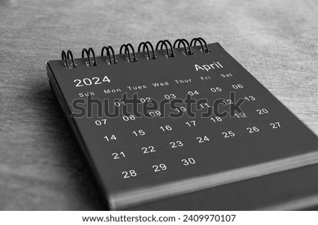 Black and white April 2024 desk calendar on wooden desk. Calendar and new month concept.