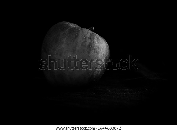 Black and\
white art photography of an apple on a black background. Artistic\
photo of fruit. Apple as a moon.\
