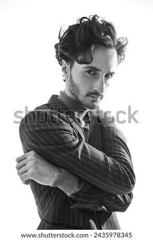 Black and white art portrait of a young man in a suit posing in a closed pose. Psychological picture. White studio background.