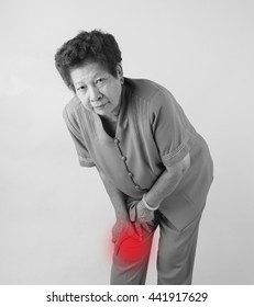 Black And White Asian Senior Woman With Leg Pain On Gray Background