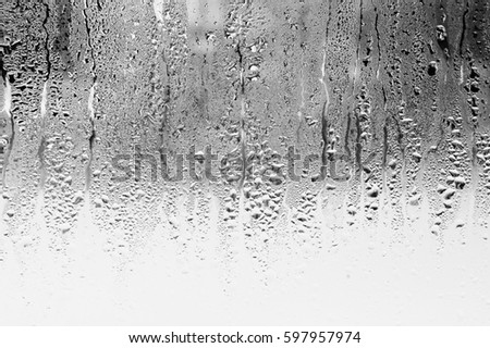 Black and white background of the condensate flowing water on the window glass