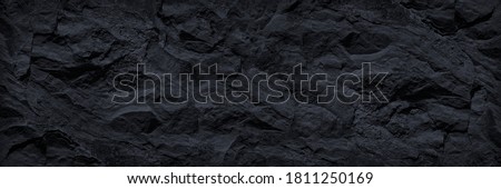 Black and white background.  Black rock texture. Close-up. Stone wall backgroud for design.  Copy space. Wide banner.